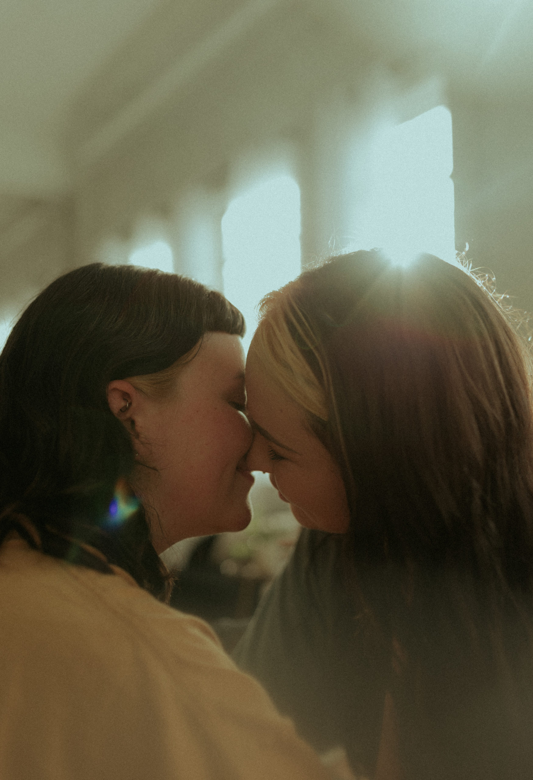 Lesbian Couple Almost Kissing by Window